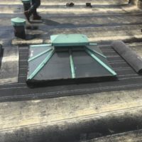 rolling out a tarp on a flat roof