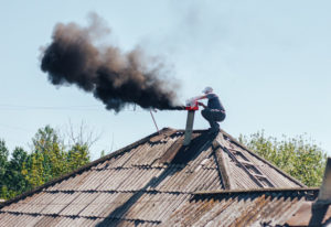 man doing a chimney sweep on an old house