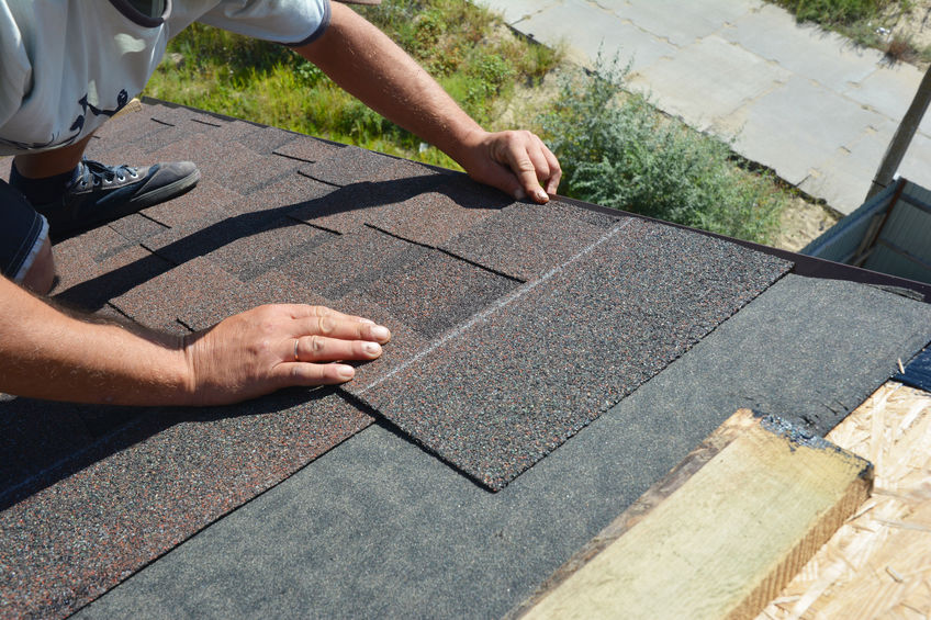 Roofer installing asphalt shingles on house construction roof corner. Roofing construction. Roofing contractor install roof tiles.