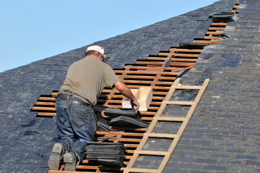 Roofer posing slate on a roof