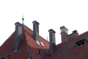 Old brick chimneys on the red roof of a historic building separated